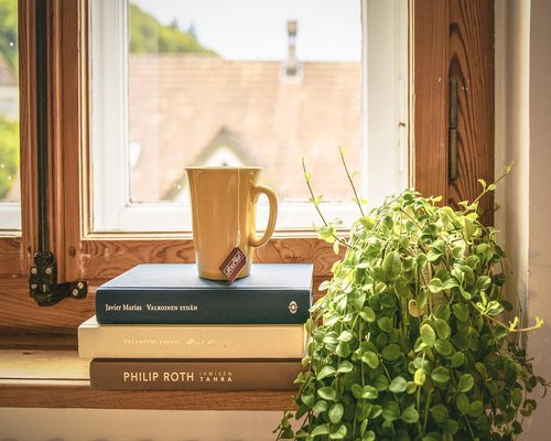 A well lit reading chair next to an open window in an apartment