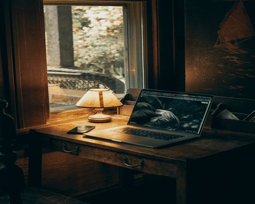 An organized work desk softly lit by a desk lamp